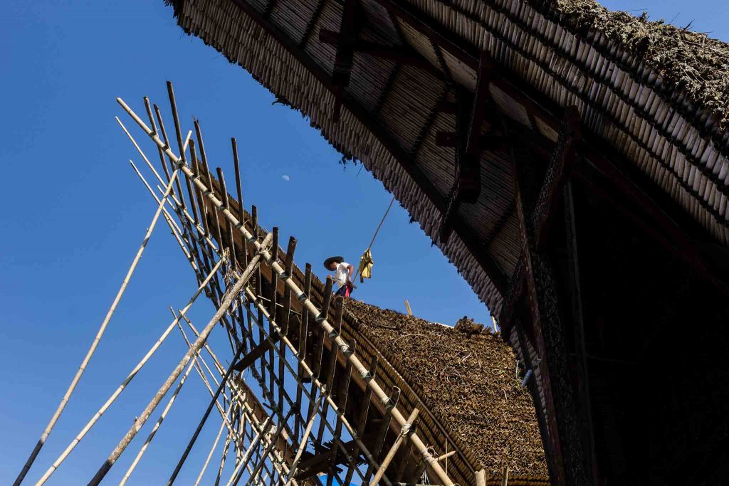 Un hombre en el tejado de una construccion tradicional de Tana Toroja Indonesia