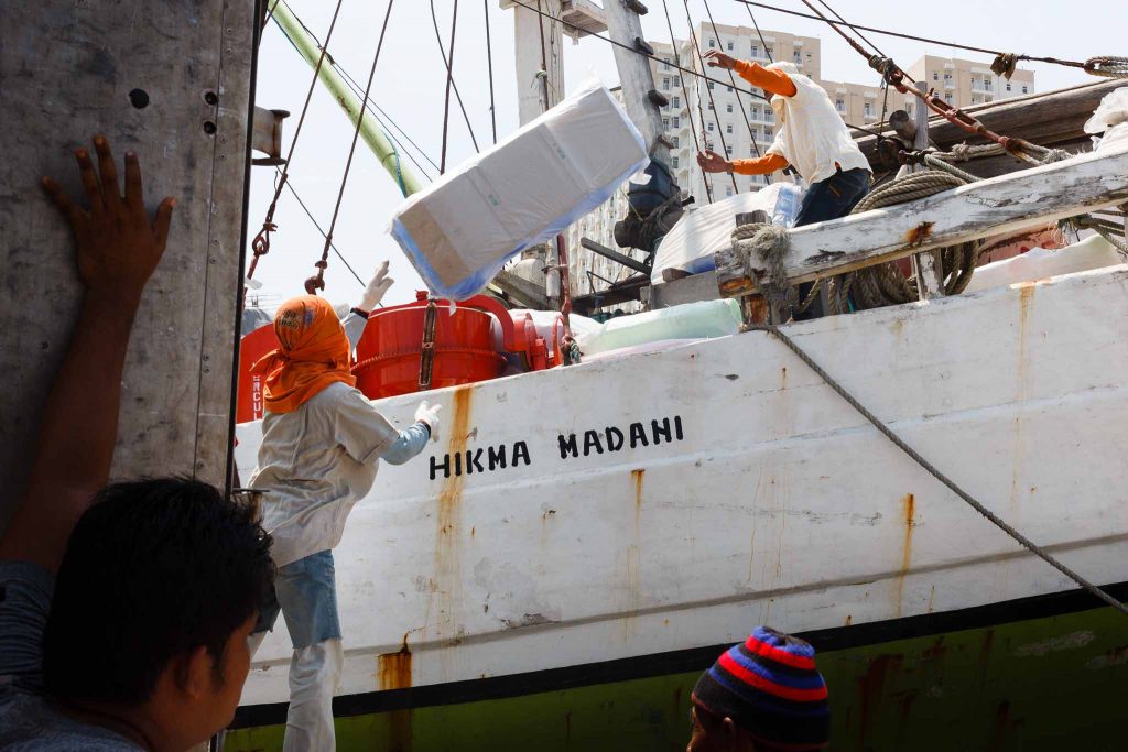 Jovenes cargando un barco en el puerto de Yakarta Indonesia