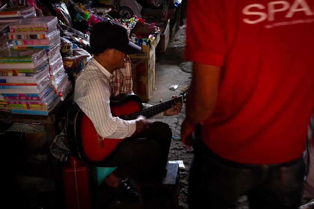 Un hombre tocando la guitarra en un mercado de callejero de Indonesia