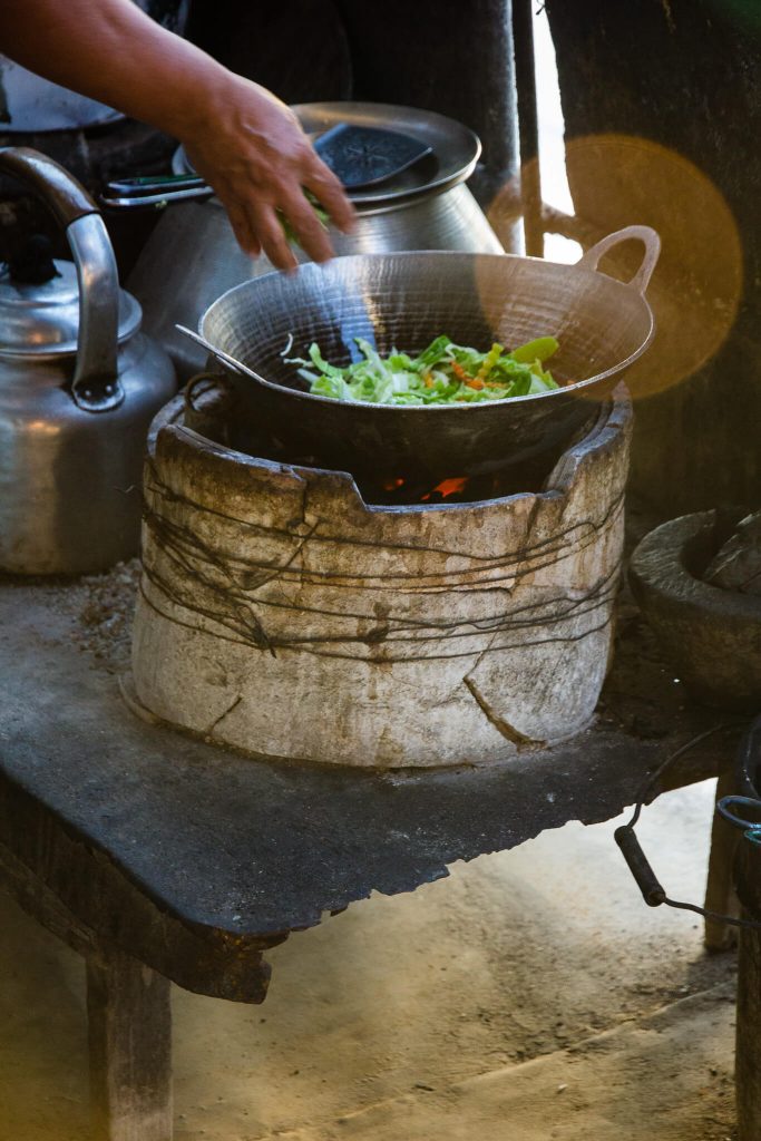 Cocina callejera en Myanmar Birmania donde una mano arroja alimentos a un wok