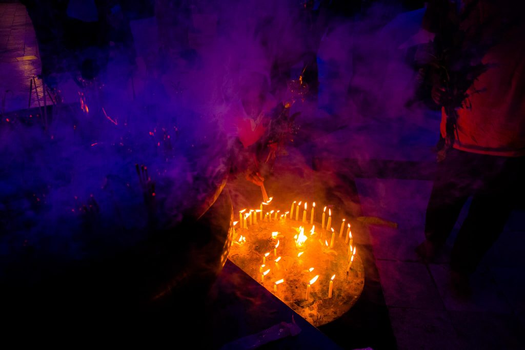 Imagen de un templo en Myanmar (Birmania) de noche con velas encendidas y humo generando una atmósfera de colores