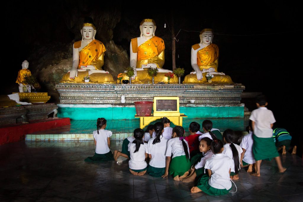 Grupo de niños en un templo en Myanmar (Birmania) con imágenes de Buda