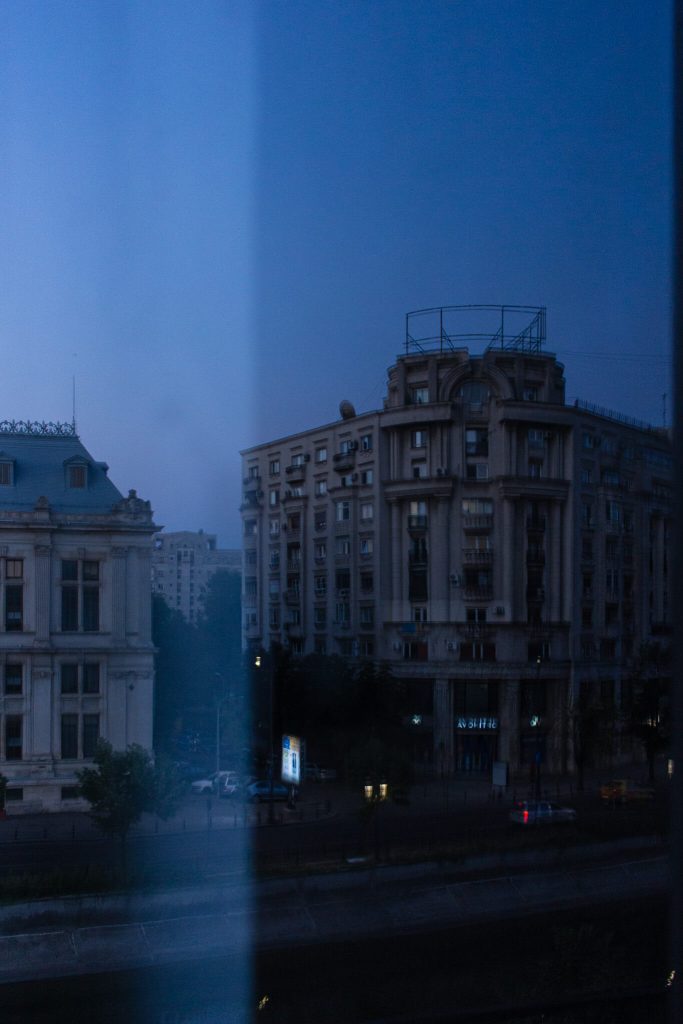 Dos edificios en la hora azul en Bucarest, Rumanía, vistos a través del filtro de una ventana