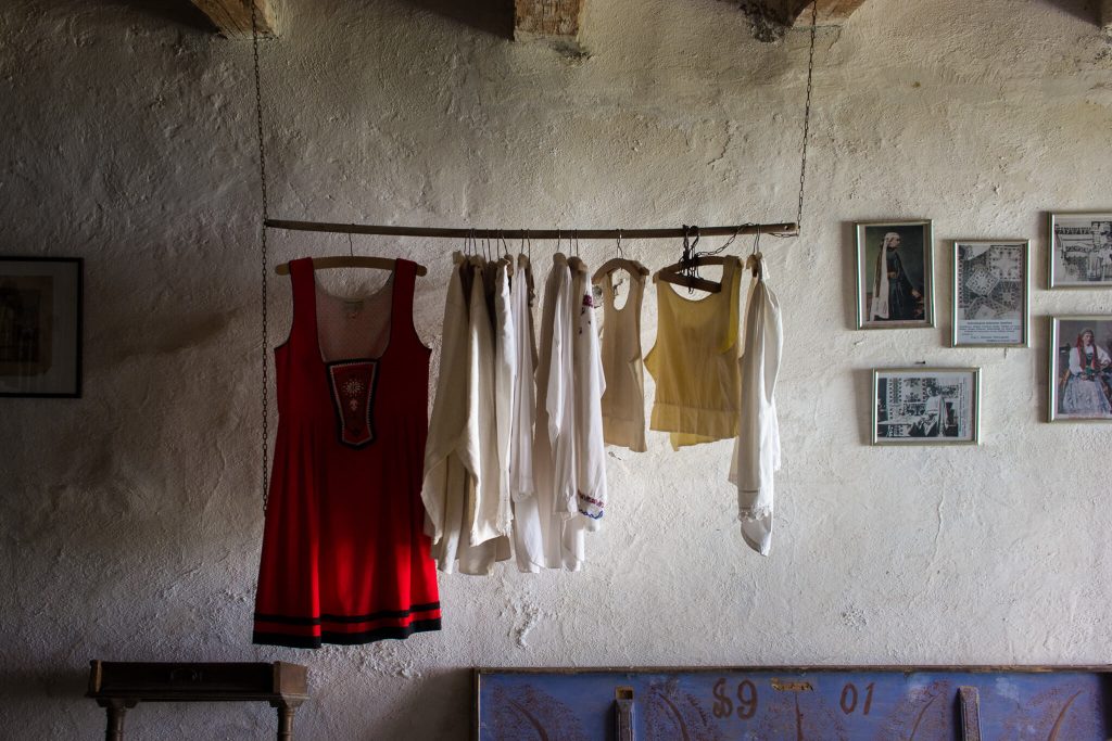 Bodegón en una habitación de una iglesia fortificada en Transilvania Rumanía donde se ve ropa tradicional colgada de una barra de madera