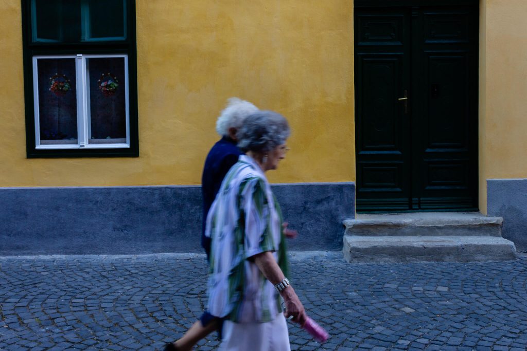 Dos mujeres en una calle de Sibiu paseando en la hora azul en una calle con empedrado y paredes amarilla
